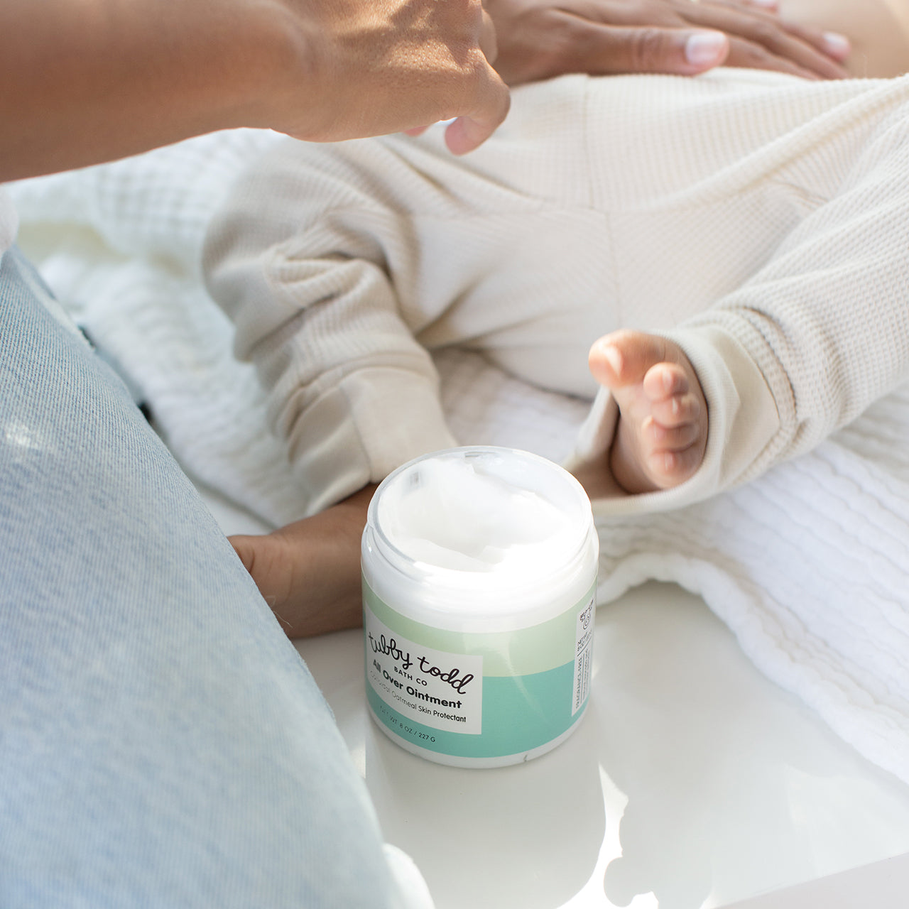 Mama applying OTC All Over Ointment on her baby's stomach